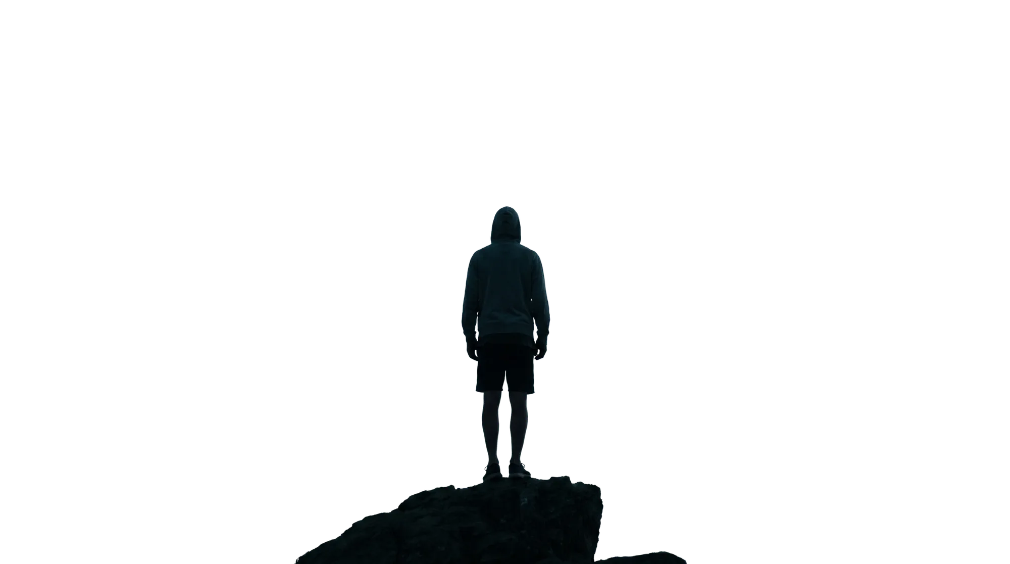 A lone hooded traveller standing on a rock, seen from behind.