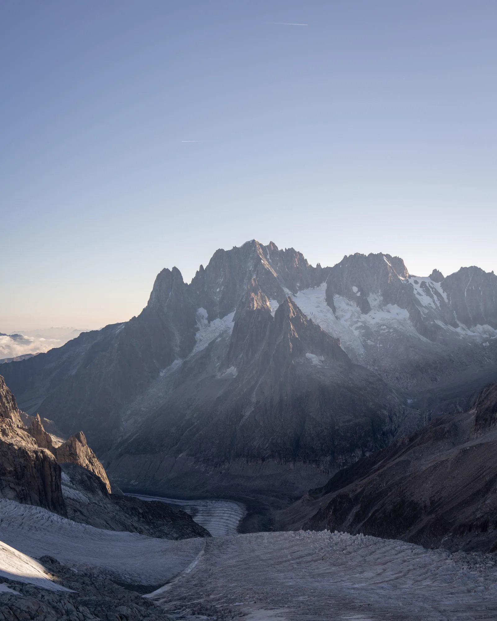 Jagged rock peaks above a glacier winding down a high alpine valley.