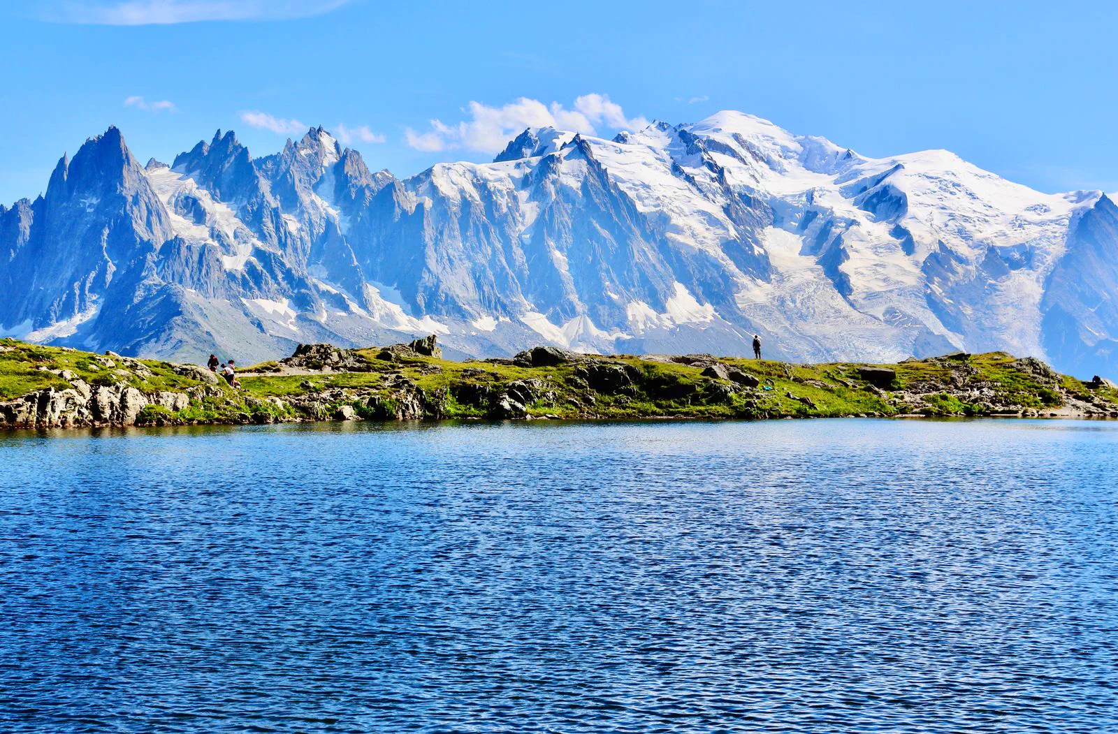 A still alpine lake reflecting the snow-covered Mont Blanc massif, a lone figure on the shore.